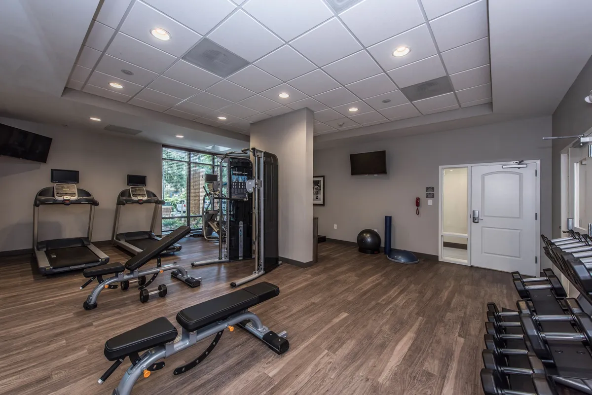 The fitness center is equipped with treadmills, a weight bench, multifunctional gym equipment, and a yoga ball. The inviting, well-lit space encourages both solo workouts and group exercise sessions.