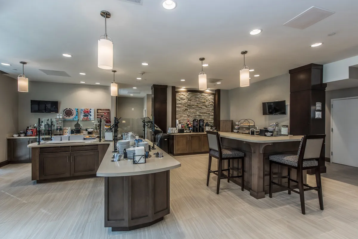 An inviting breakfast bar and coffee station with comfortable seating and a decorative wall, designed for guests to enjoy coffee, breakfast, or casual gatherings. The atmosphere is relaxed, with space for both solo moments and social opportunities.