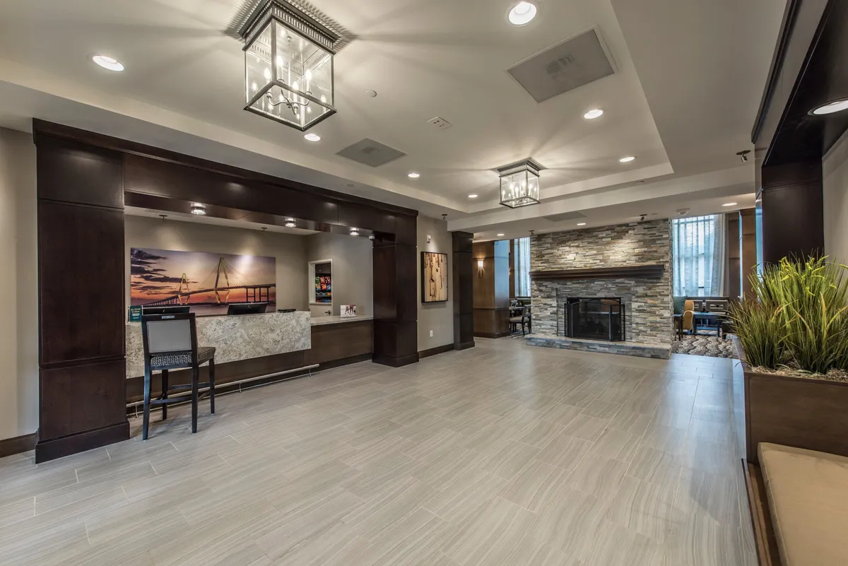 This image features the hotel lobby's reception desk, a welcoming fireplace, stylish artwork, and a comfortable seating area. The inviting ambiance sets the tone for a warm arrival and highlights the hospitality guests experience upon check-in.